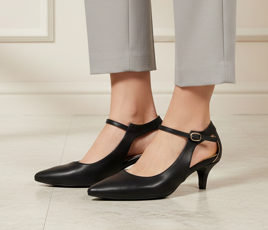 Black high-heeled shoes worn with gray pants on a neutral background